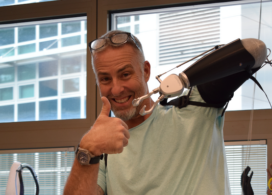 Man wearing ProHensor terminal device smiles and gives thumbs up with natural hand.
