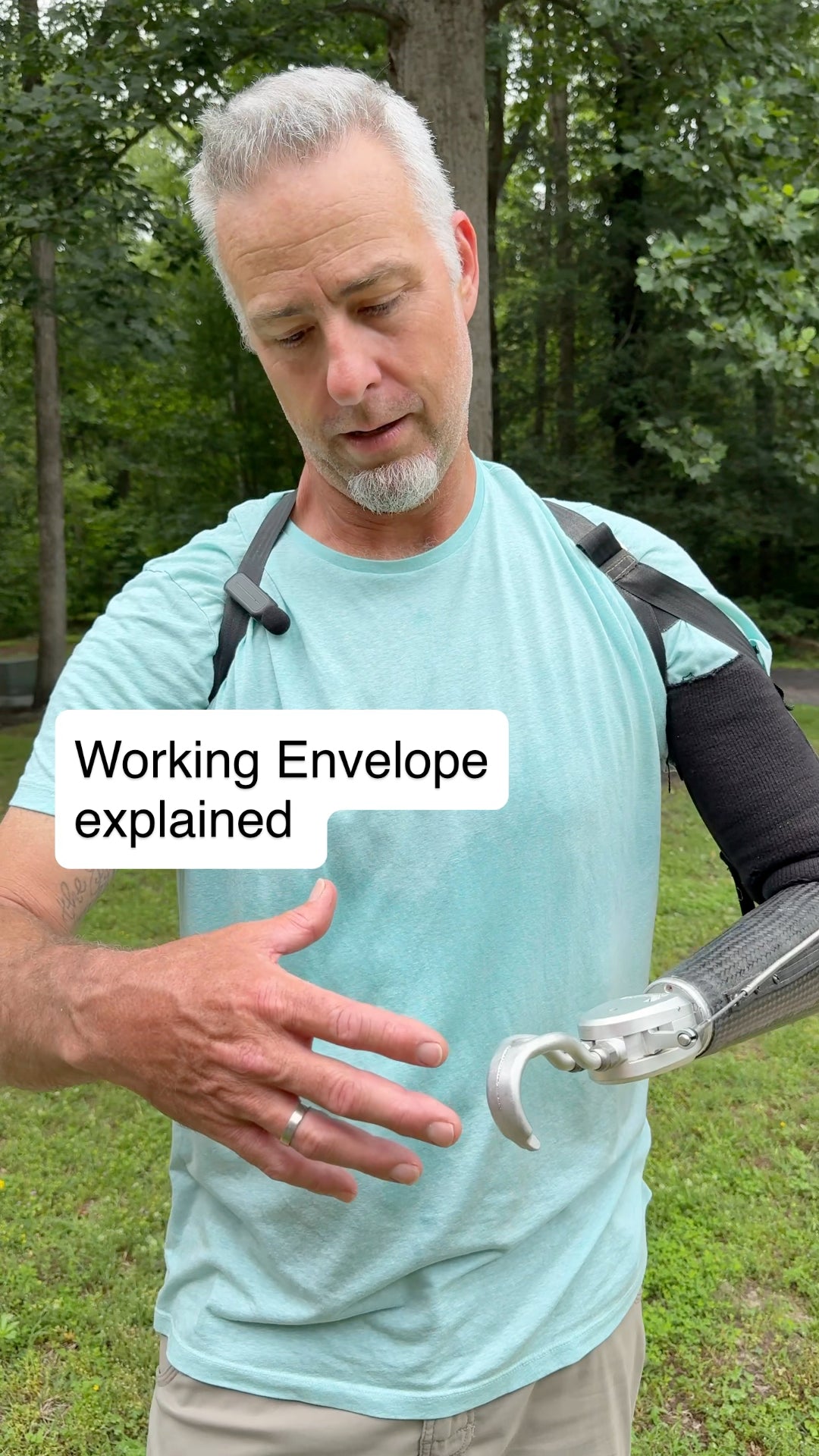 Man with a body-powered prosthetic arm explaining 'Working Envelope'. outdoors.